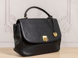 a black handbag sitting on top of a wooden table