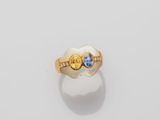a close up of a gold ring with two blue and yellow stones