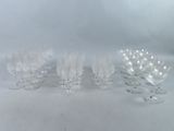 six verres à vin transparents sont alignés sur une surface blanche