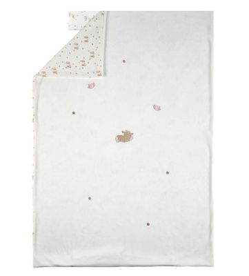 un gros plan sur une couverture blanche sur laquelle se trouve un ours en peluche