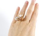 a woman ' s hand holding a ring with a pearl on it
