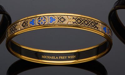 two gold and blue enamel bang bracelets on a black surface