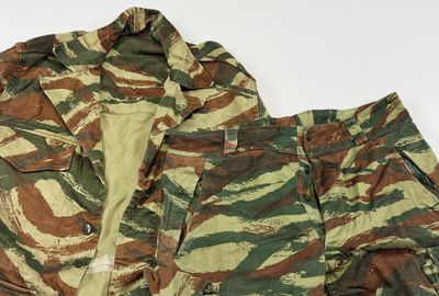 une photo d'une veste et d'un pantalon de camouflage posés sur une surface blanche