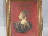 an old picture of a woman in a black dress in a gold frame