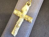 une croix en or posée sur un tissu gris, sur une table