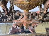 a bronze vase on a stand with a mirror in front of it