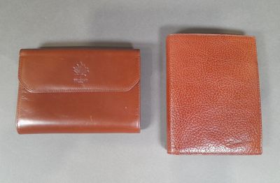 two brown leather wallets sitting next to each other on a table