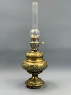 une lampe à huile ancienne en laiton, surmontée d'un globe en verre transparent