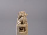 carved ivory figurine of a lion on a pedestal on a gray background