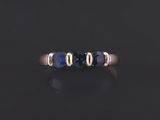 a gold ring with three blue sapphire stones on a black surface