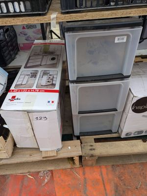 Plusieurs micro-ondes et autres appareils électroménagers sont empilés sur des palettes dans un magasin