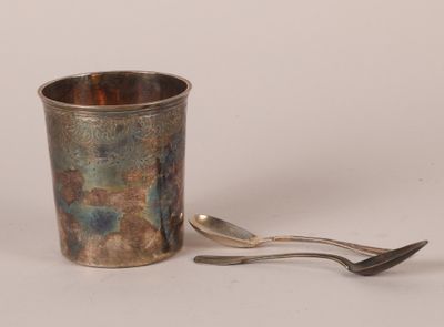 une tasse en argent avec une cuillère posée à côté