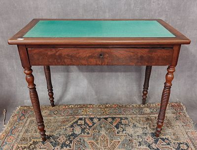 une vieille table en bois avec un plateau en verre vert, posée sur un tapis