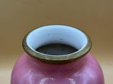 a pink vase with a gold rim sitting on a table
