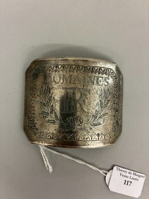 un gros plan sur une boucle de ceinture en argent à laquelle est accrochée une étiquette
