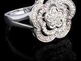 un gros plan d'une bague ornée d'une fleur en diamant posée sur une surface noire