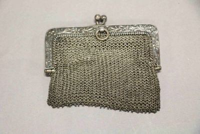 un porte-monnaie argenté entouré d'une chaîne, posé sur une surface blanche