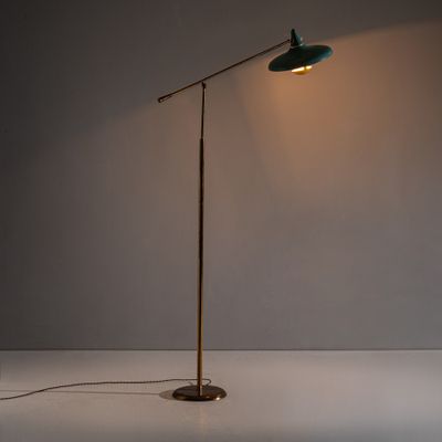 un lampadaire vert posé sur une surface blanche, devant un mur blanc