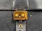 a close up of a black leather bag with a gold clasp