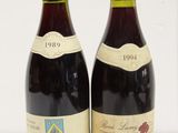 two bottles of red wine sitting next to each other on a table