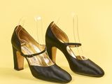 une paire de chaussures noires à talons transparents sur fond jaune