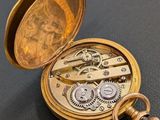 an image of a gold pocket watch on a black surface