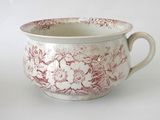 a red and white bowl with a handle on a white table