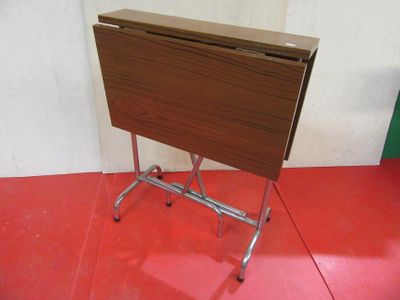 a small folding table on a metal stand on a red floor