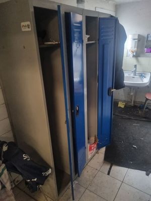 deux casiers bleus dans une salle de bains, avec un sac noir posé par terre