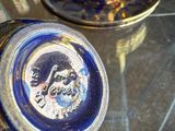 a person holding a blue and gold cup and saucer