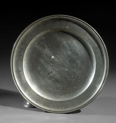 silver plate sitting on top of a white surface with a black background