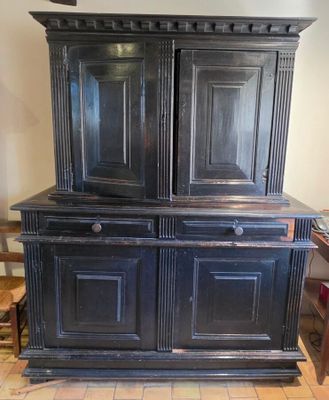 une vieille armoire noire à deux portes et un tiroir