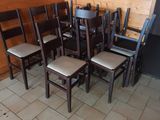 several wooden chairs are lined up against a wall in a restaurant