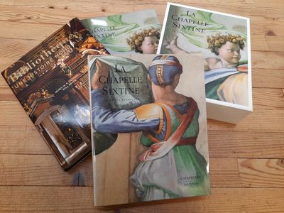 trois livres posés sur une table en bois, avec la photo d'une femme en robe