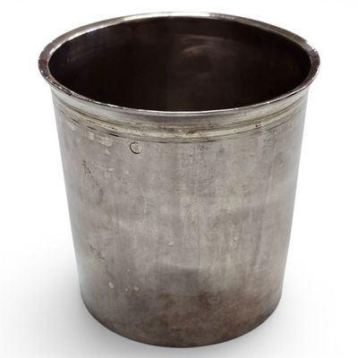 a metal cup that is sitting on a white surface