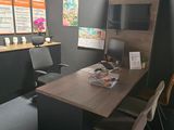 a desk with chairs and a television in a room