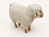a stuffed sheep that is standing on a white surface