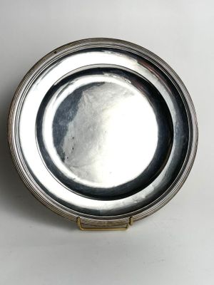 a silver plate with a handle on a white surface
