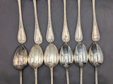 six silver spoons are arranged in a row on a black surface