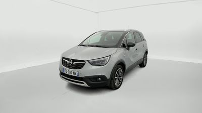 Une voiture argentée est garée dans une pièce blanche au sol blanc.