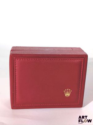 Le portefeuille rouge, orné d'une couronne, est posé sur une surface blanche.