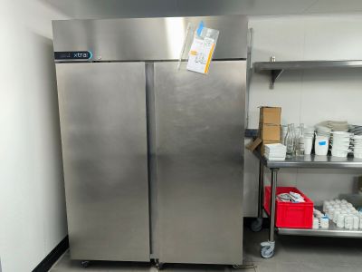 des réfrigérateurs en acier inoxydable dans une cuisine professionnelle, avec une étagère remplie de produits alimentaires