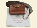 brown leather purse sitting on top of a white bag next to a black and white bag