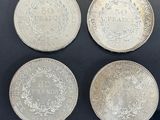 four silver coins are on display in a glass case
