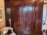 a chair in the corner of a room with a large wooden armoire