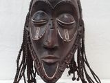 un gros plan d'un masque en bois posé sur un socle, sur une table