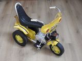 un petit tricycle jaune avec un siège noir posé sur un plancher en bois