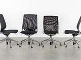 four black office chairs in a row against a white wall