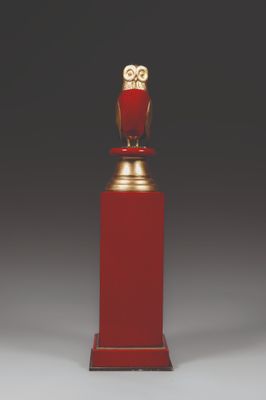 une figurine de chouette sur un socle à base rouge