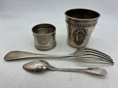 une tasse en argent, une cuillère et un repose-cuillère posés sur une table